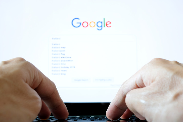 hands typing into google search on the computer